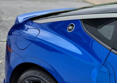 A blue car being detailed by a worker with a polishing machine.