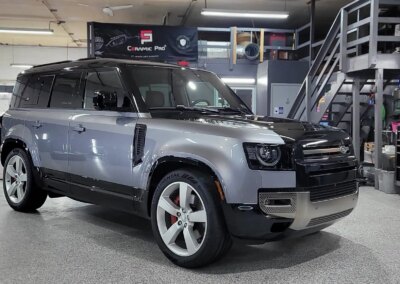 A car with a glossy finish after detailing, parked in front of Total Detailing shop.