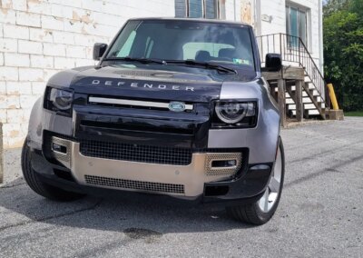 A car with shiny black paint undergoing detailing in a well-equipped garage.