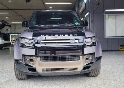 A car undergoing detailing in a professional garage with equipment and products visible.