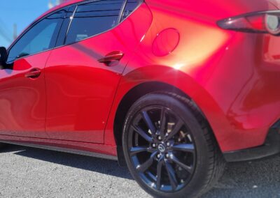 A red sports car being detailed by a professional at Total Detailing Auto Spa.