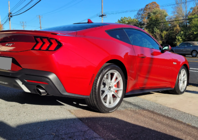 A blue Mustang with paint protection film applied to the hood and front bumper.