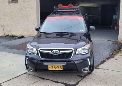 A shiny black car with detailed exterior and reflection on the hood.